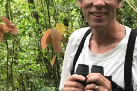 Portrait of Philip Stoddard ’79 holding binoculars. 